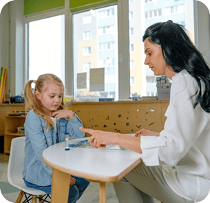 Specialist working one-on-one with a young girl at a classroom table